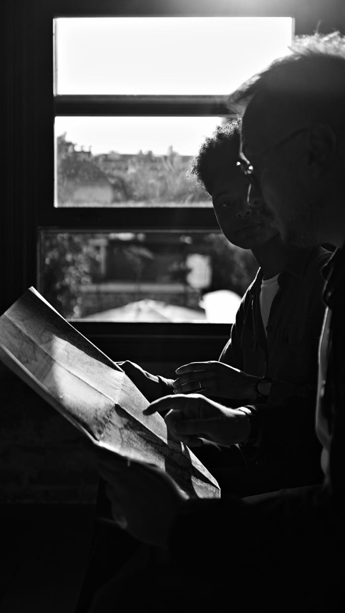 Crafting Captivating Headlines: Your awesome post title goes here Two people study a map in a silhouette against a sunlit window, suggesting planning or exploration.